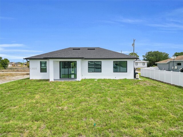 4115 20th St SW, Lehigh Acres, FL 33397 - rear view of property with a yard, stucco siding, a shingled roof, and fence