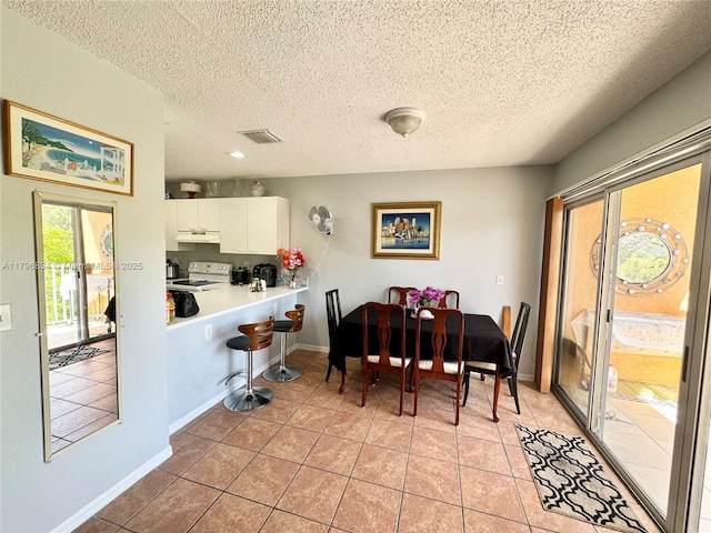 dining room featuring a textured ceiling, baseboards, light tile patterned floors, and visible vents