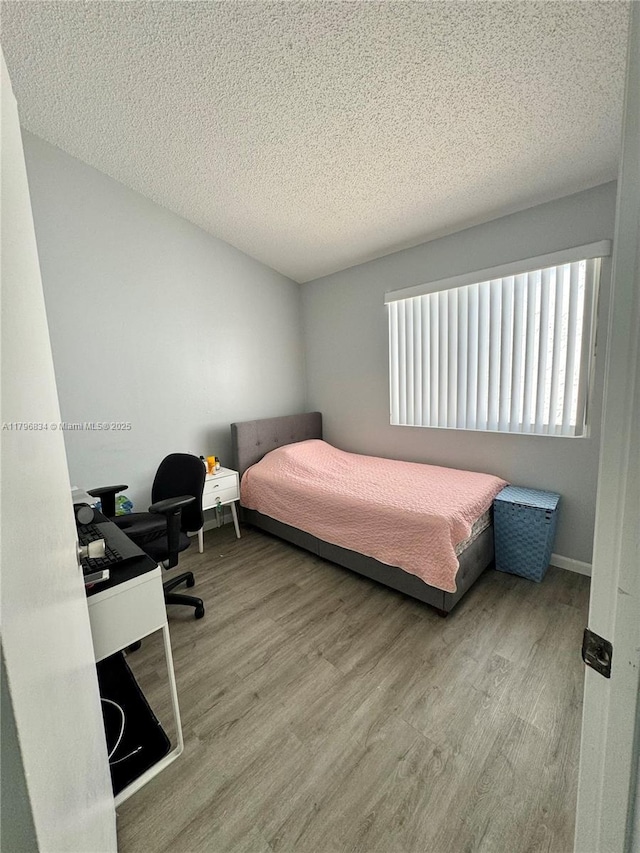 bedroom featuring a textured ceiling and wood finished floors
