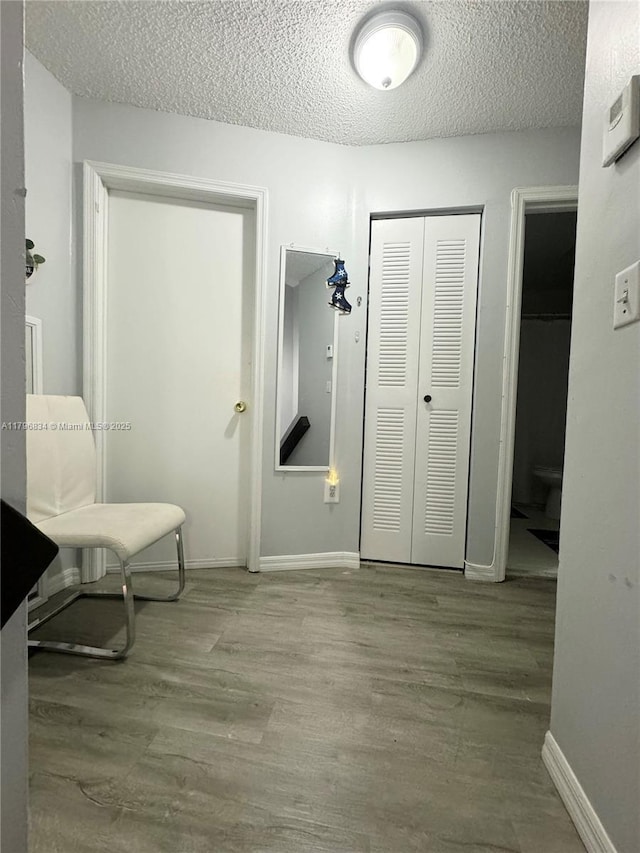 interior space featuring a textured ceiling, wood finished floors, and baseboards