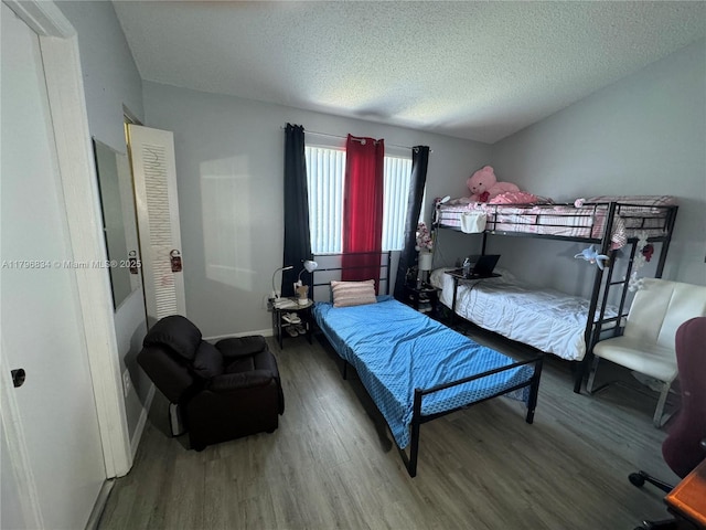 bedroom featuring a textured ceiling, wood finished floors, and baseboards
