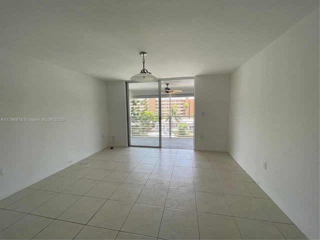 spare room featuring light tile patterned floors, a wall of windows, and ceiling fan