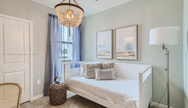 carpeted bedroom featuring baseboards and a chandelier
