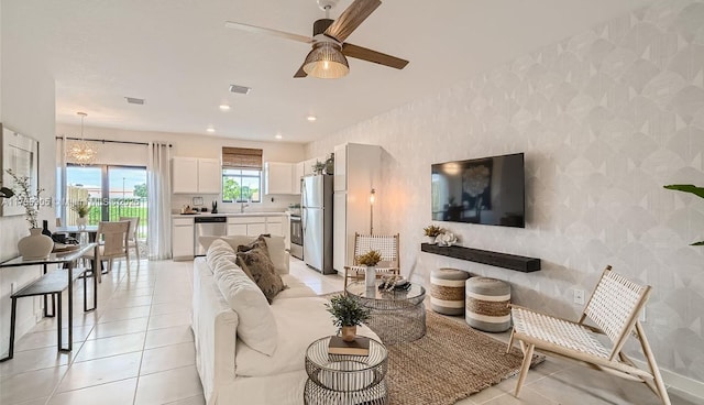 living room with light tile patterned flooring, wallpapered walls, visible vents, and ceiling fan with notable chandelier