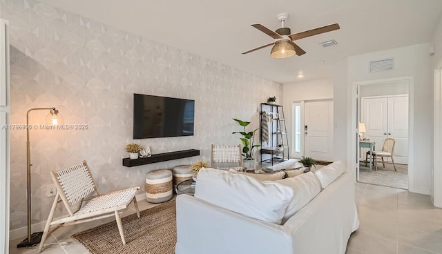 living area with baseboards, ceiling fan, visible vents, and wallpapered walls