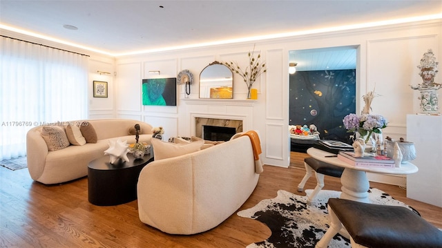 living room featuring a fireplace, a decorative wall, and light wood-type flooring