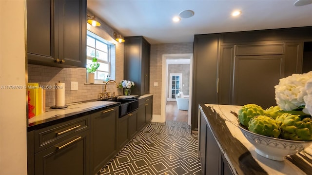 kitchen featuring a sink, dark floors, light stone countertops, backsplash, and recessed lighting