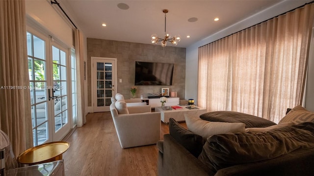 living room with french doors, light wood finished floors, an inviting chandelier, and recessed lighting