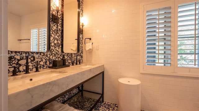bathroom featuring tile walls, plenty of natural light, and a sink