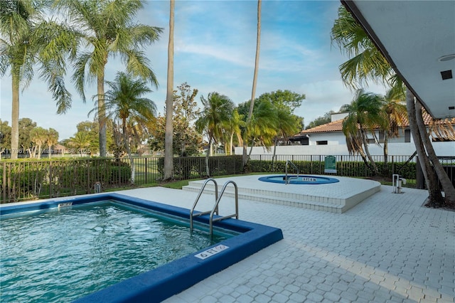 pool with a hot tub, fence, and a patio area