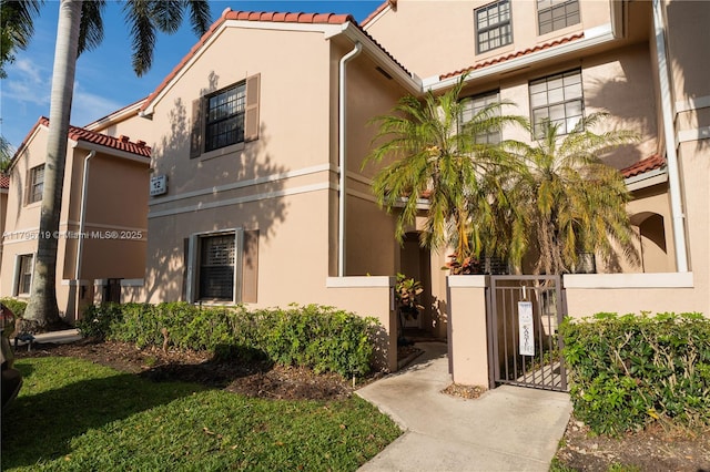 view of front of home featuring a gate, fence, stucco siding, and a tiled roof