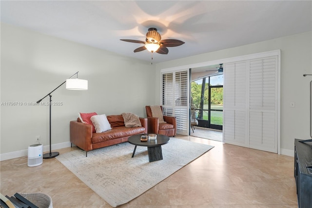 living area featuring baseboards and ceiling fan