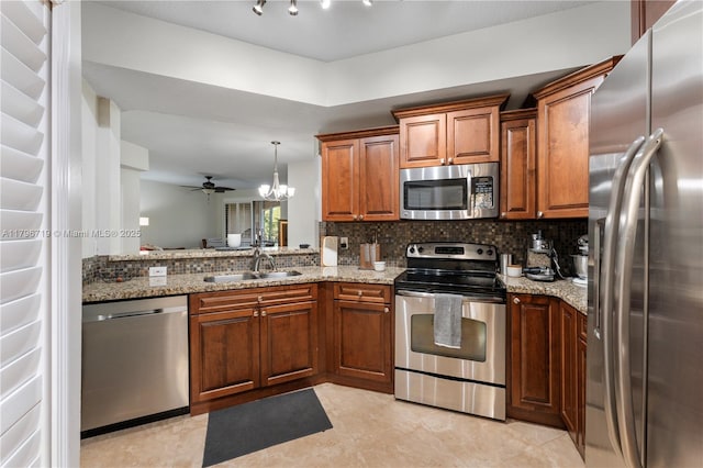 kitchen with light stone counters, a sink, decorative backsplash, brown cabinets, and stainless steel appliances
