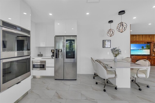 5101 N 37th St, Hollywood, FL 33021 - kitchen with a kitchen bar, white cabinetry, modern cabinets, light countertops, and appliances with stainless steel finishes