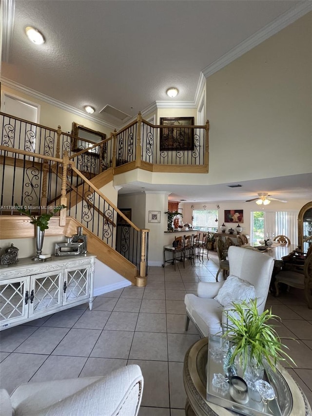 living area with stairway, tile patterned flooring, a towering ceiling, and ornamental molding