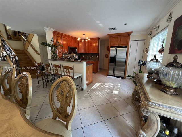 kitchen featuring light tile patterned floors, visible vents, a peninsula, tasteful backsplash, and appliances with stainless steel finishes