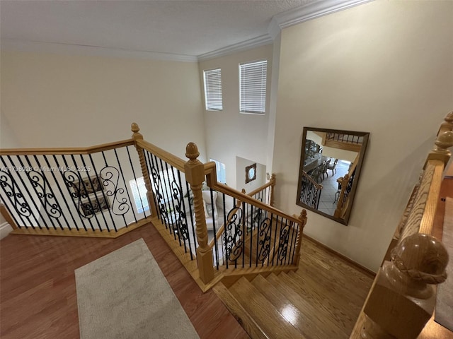 staircase with crown molding, baseboards, and wood finished floors