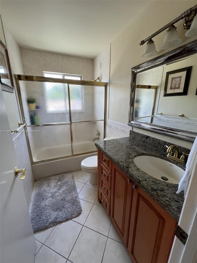 bathroom with enclosed tub / shower combo, vanity, toilet, and tile patterned floors