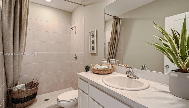 bathroom with vanity, toilet, and tiled shower