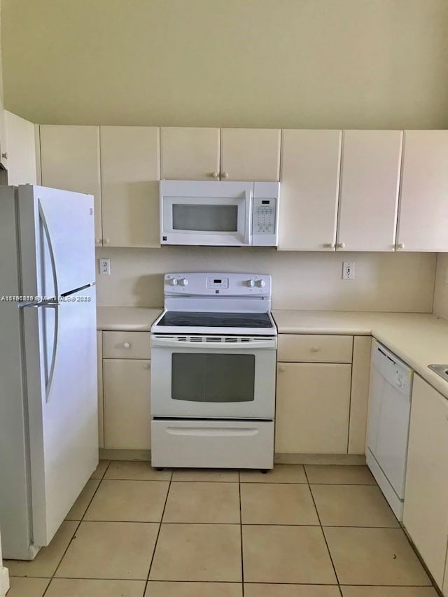 kitchen featuring light tile patterned floors, white appliances, light countertops, and white cabinetry