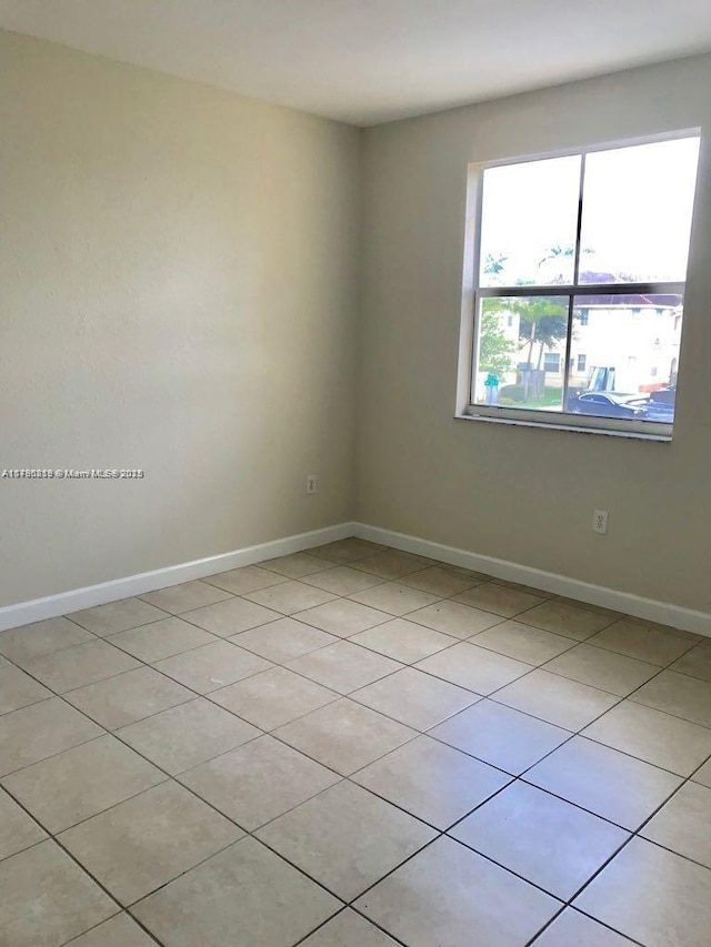 unfurnished room featuring light tile patterned floors and baseboards