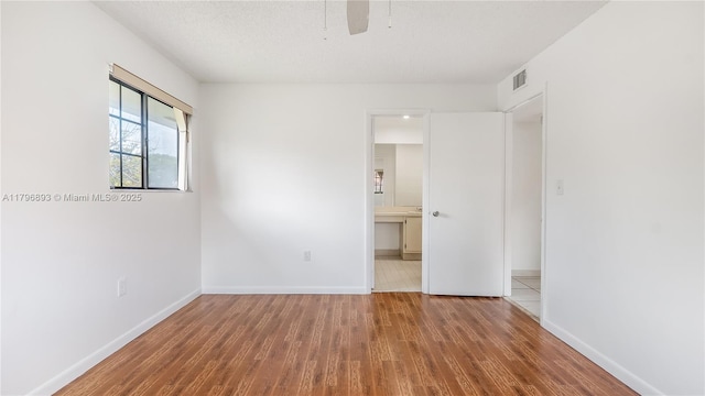 unfurnished bedroom with baseboards, visible vents, a ceiling fan, and wood finished floors