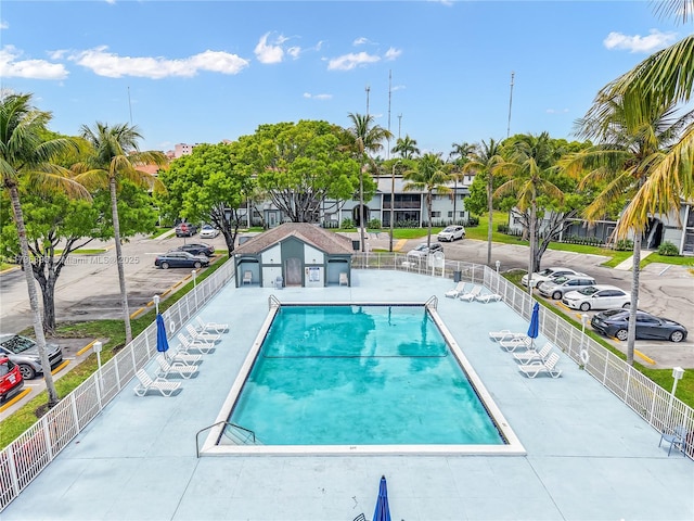 community pool with a patio area and fence