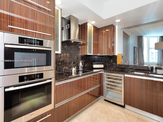 kitchen with beverage cooler, stainless steel double oven, wall chimney range hood, black electric cooktop, and tasteful backsplash