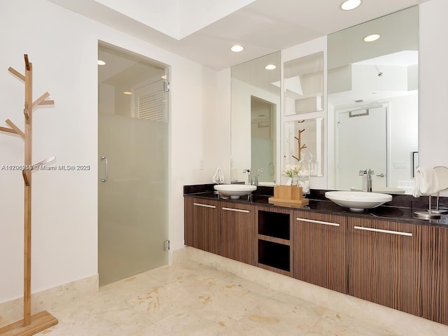 full bath featuring a shower stall, recessed lighting, a sink, and double vanity