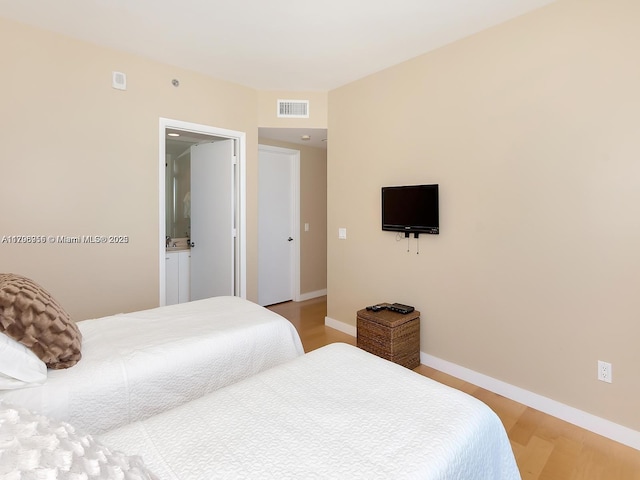 bedroom featuring light wood finished floors, visible vents, and baseboards
