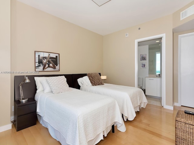 bedroom featuring baseboards, light wood finished floors, connected bathroom, and visible vents