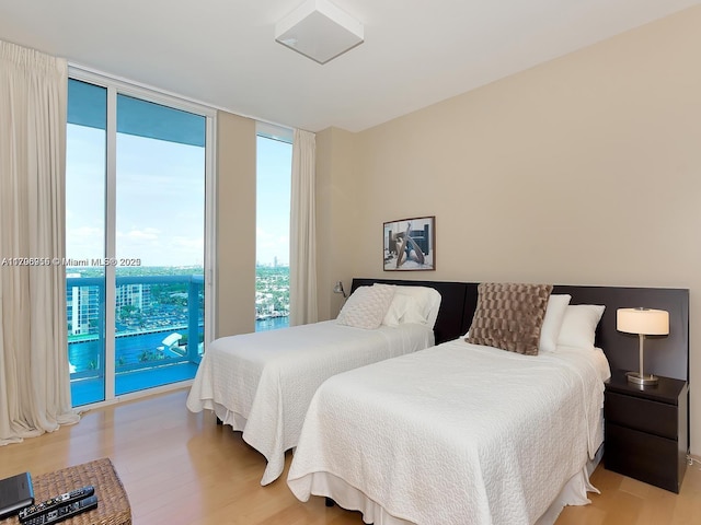 bedroom with a wall of windows, access to outside, and wood finished floors