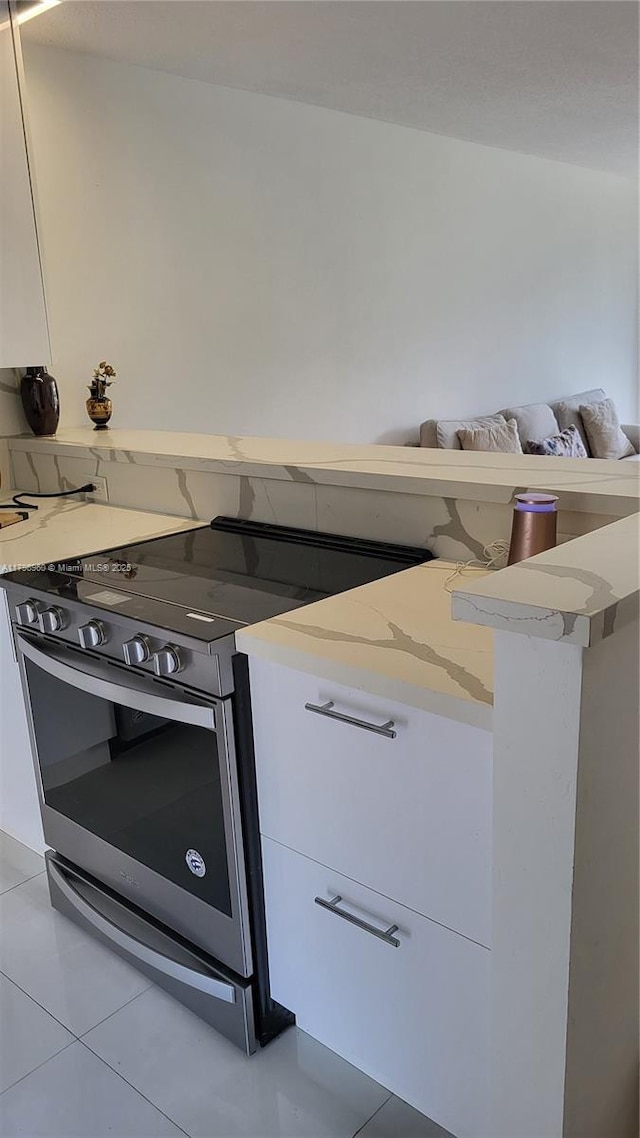 3401 N Country Club Dr Unit 410, Aventura, FL 33180 - kitchen featuring light stone countertops, white cabinetry, light tile patterned floors, and electric range