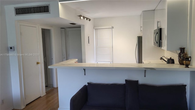 3401 N Country Club Dr Unit 410, Aventura, FL 33180 - kitchen with a peninsula, visible vents, stainless steel microwave, and a kitchen breakfast bar