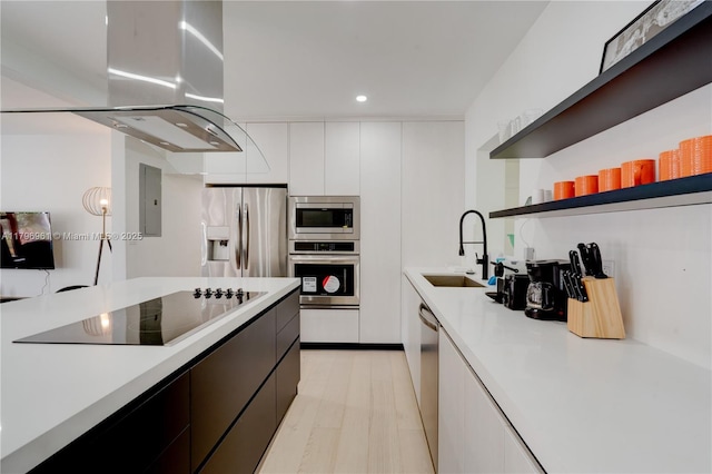 kitchen featuring a sink, island range hood, light countertops, modern cabinets, and appliances with stainless steel finishes