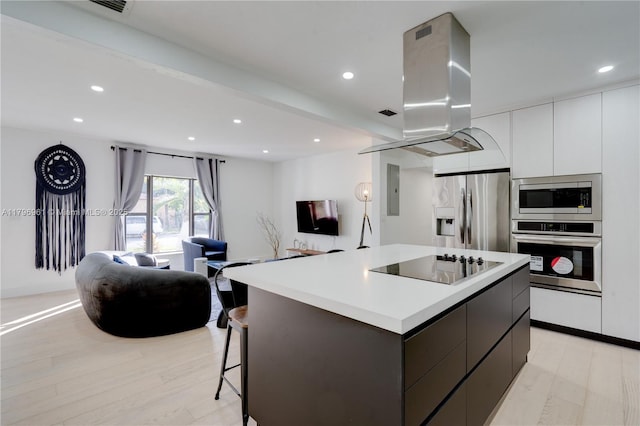 kitchen with island range hood, open floor plan, a kitchen island, modern cabinets, and appliances with stainless steel finishes