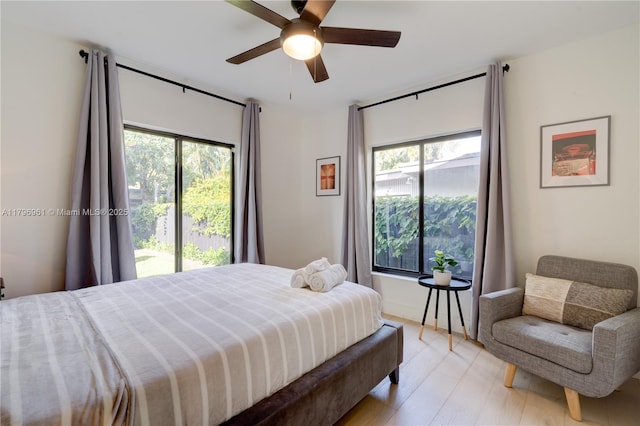 bedroom with light wood-type flooring, ceiling fan, access to exterior, and multiple windows