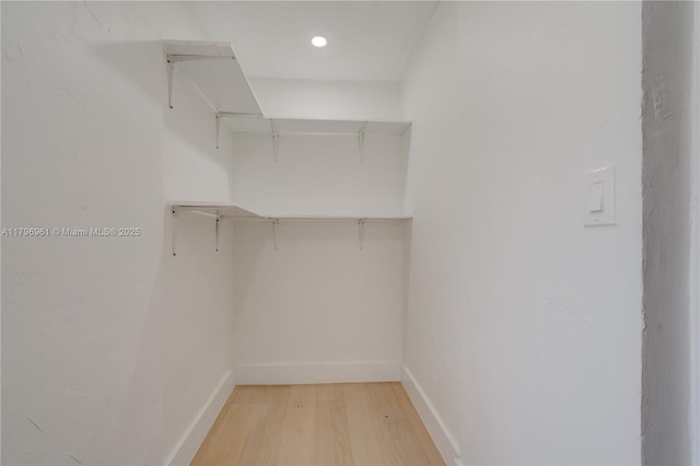 walk in closet with light wood finished floors