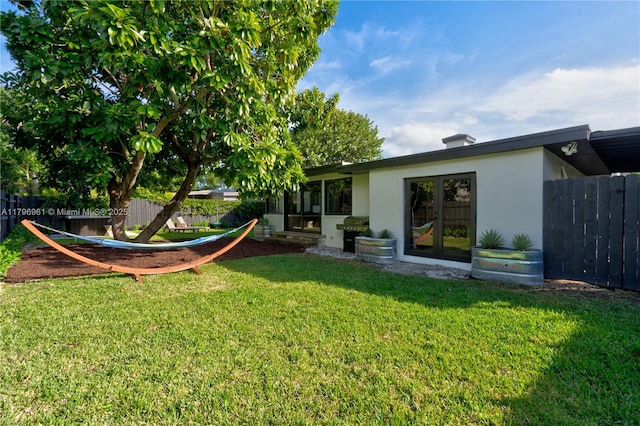 view of yard featuring french doors and fence