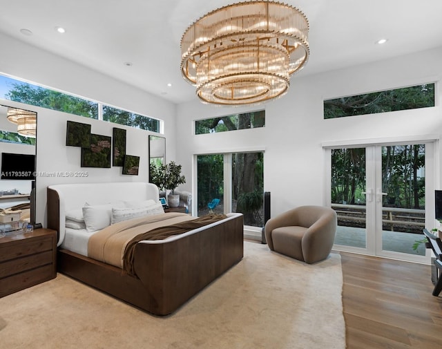 bedroom with wood finished floors, a high ceiling, french doors, and recessed lighting