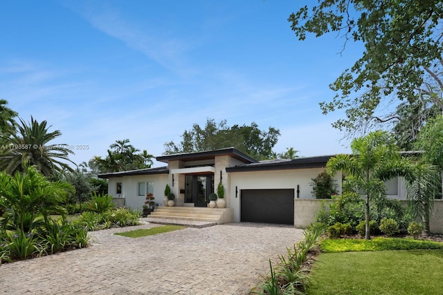 prairie-style home featuring an attached garage, stucco siding, and decorative driveway