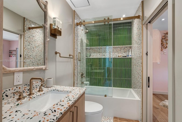 bathroom with toilet, enclosed tub / shower combo, wood finished floors, vanity, and recessed lighting