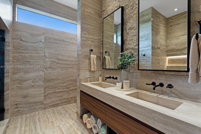 bathroom with a sink, double vanity, and tile walls