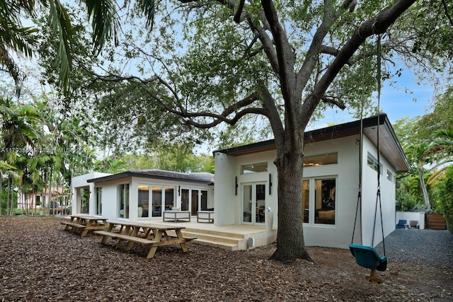 back of house featuring stucco siding and french doors