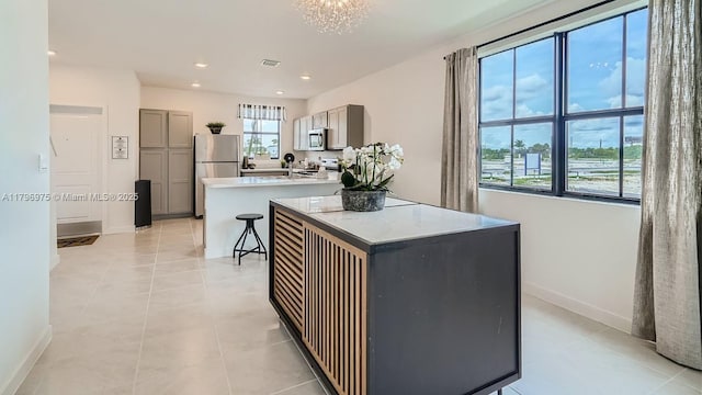 kitchen featuring a peninsula, gray cabinets, recessed lighting, baseboards, and appliances with stainless steel finishes
