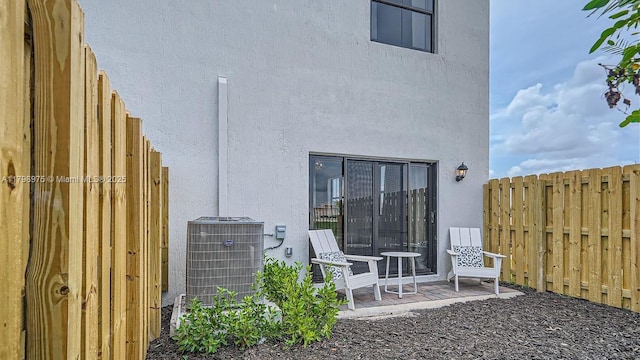 rear view of property featuring fence, stucco siding, and cooling unit