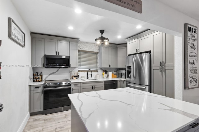 kitchen featuring recessed lighting, gray cabinetry, baseboards, a sink, and stainless steel appliances