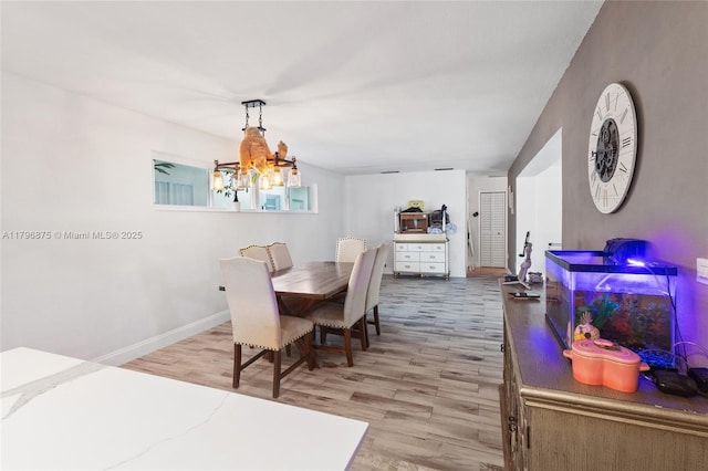 dining space featuring baseboards, light wood-style floors, and a chandelier