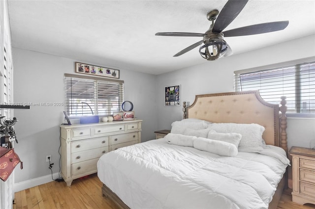 bedroom with light wood-style floors, ceiling fan, baseboards, and multiple windows