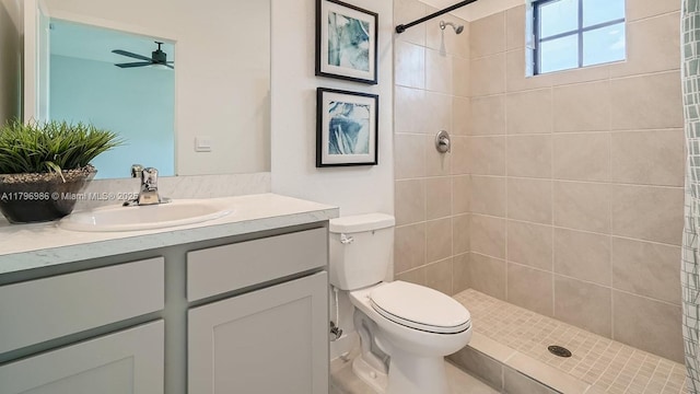 bathroom with vanity, toilet, a tile shower, and ceiling fan